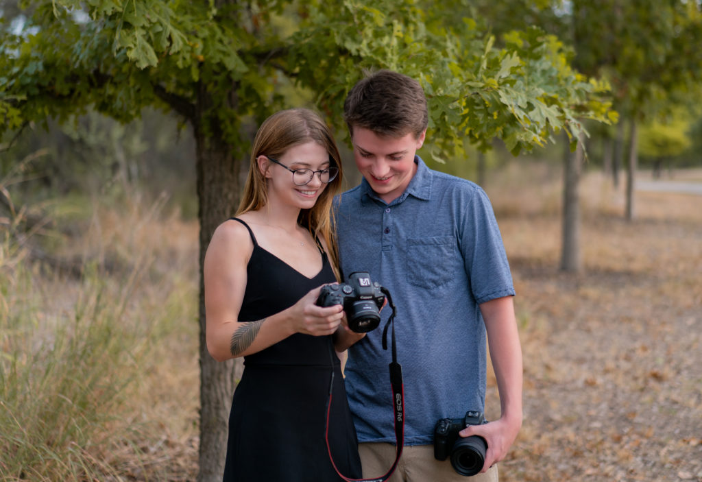 A wedding photographer and videographer look at a camera together