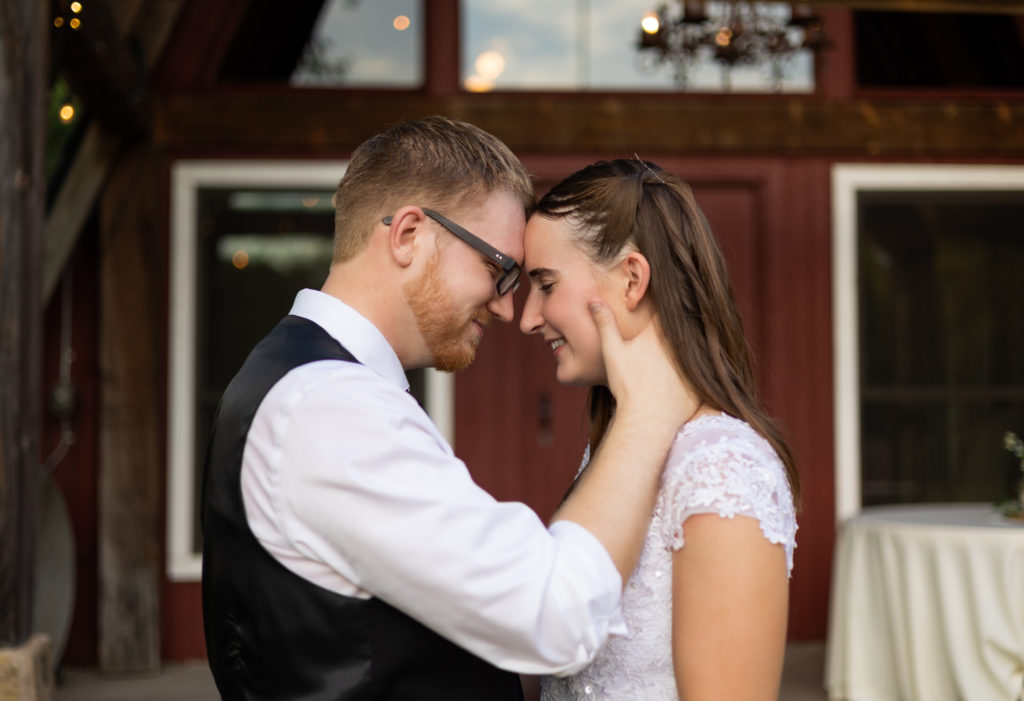 A bride and groom touching foreheads in front of a barn in Austin