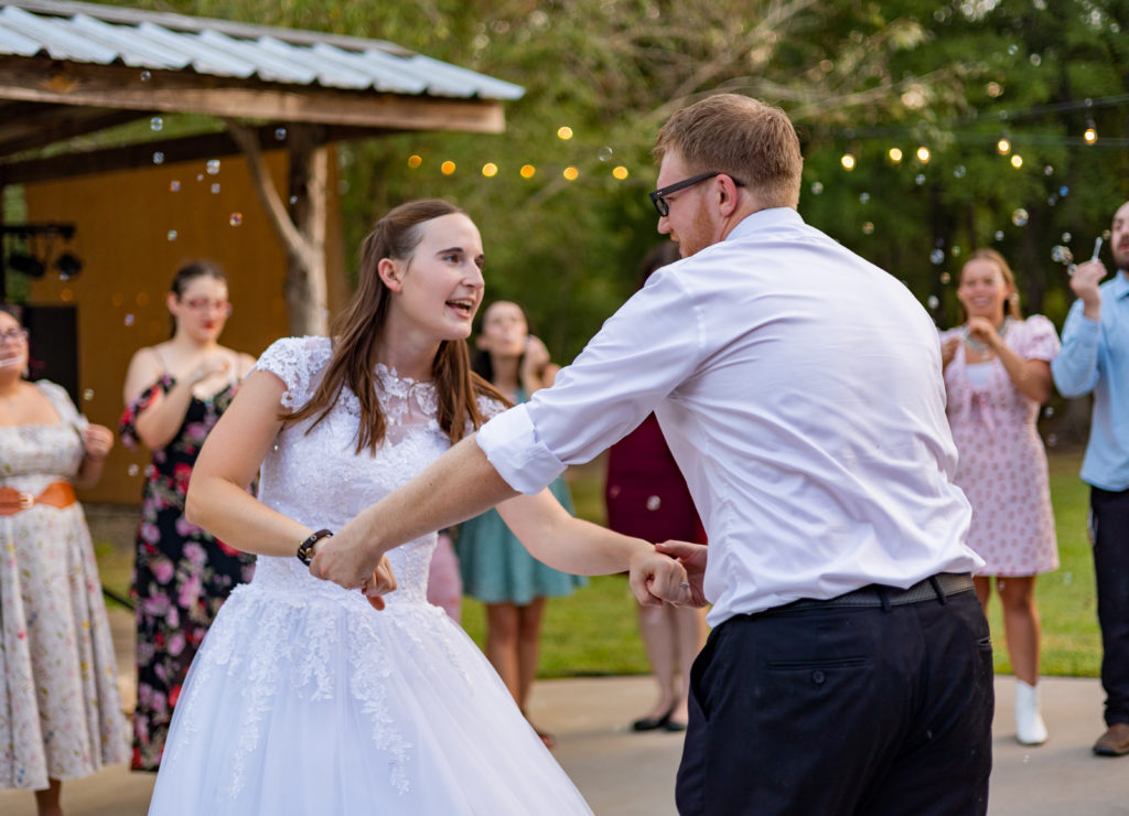 A bride and groom dance while guests blow bubbles at them