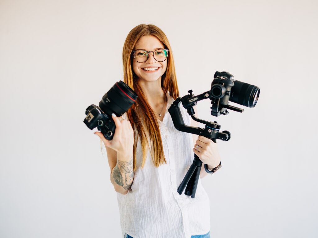 A professional wedding photographer holds two canon mirrorless cameras during branding photos. One camera is on a gimbal stabilizer.