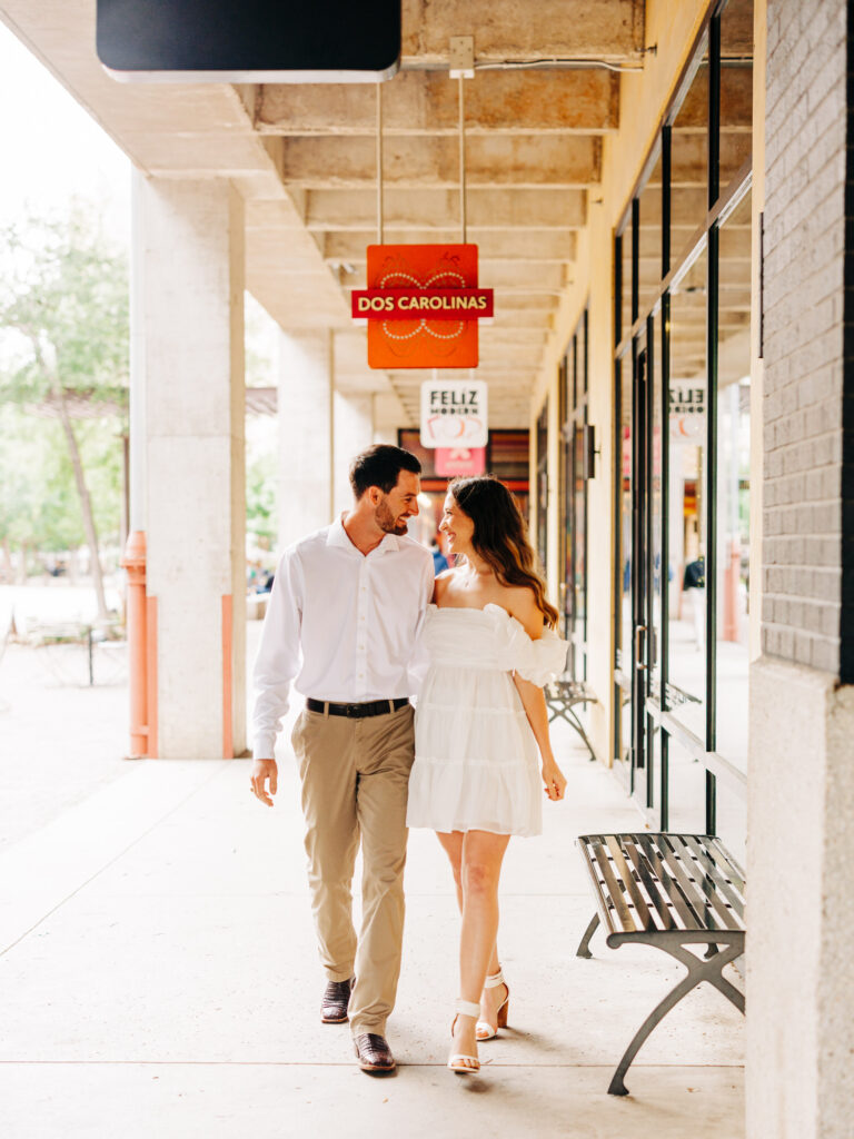 A man and a woman walking together lovingly next to the shops at the Pearl in San Antonio. The couple is looking at each other.