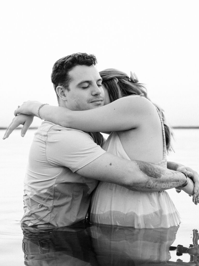 A black-and-white image of the couple embracing in Canyon Lake, their eyes closed as they hold each other closely, creating a peaceful and intimate moment.